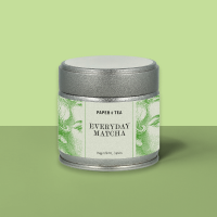 Silberne Dose mit grünem Blatt-Design und Aufschrift 'EVERYDAY MATCHA' vor grünem Hintergrund.