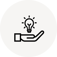 Eine schwarze Hand hält eine leuchtende Glühbirne auf weißem Hintergrund, Symbol für Innovation.