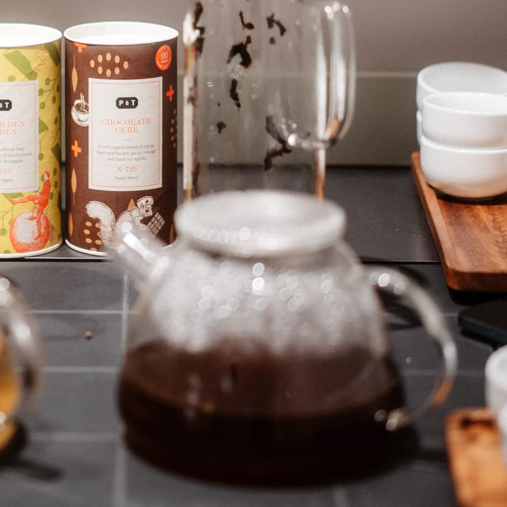 Bunte Teedosen für koffeinfreien Liebesapfel- und Lindenblütentee, mit Teekanne im Hintergrund.