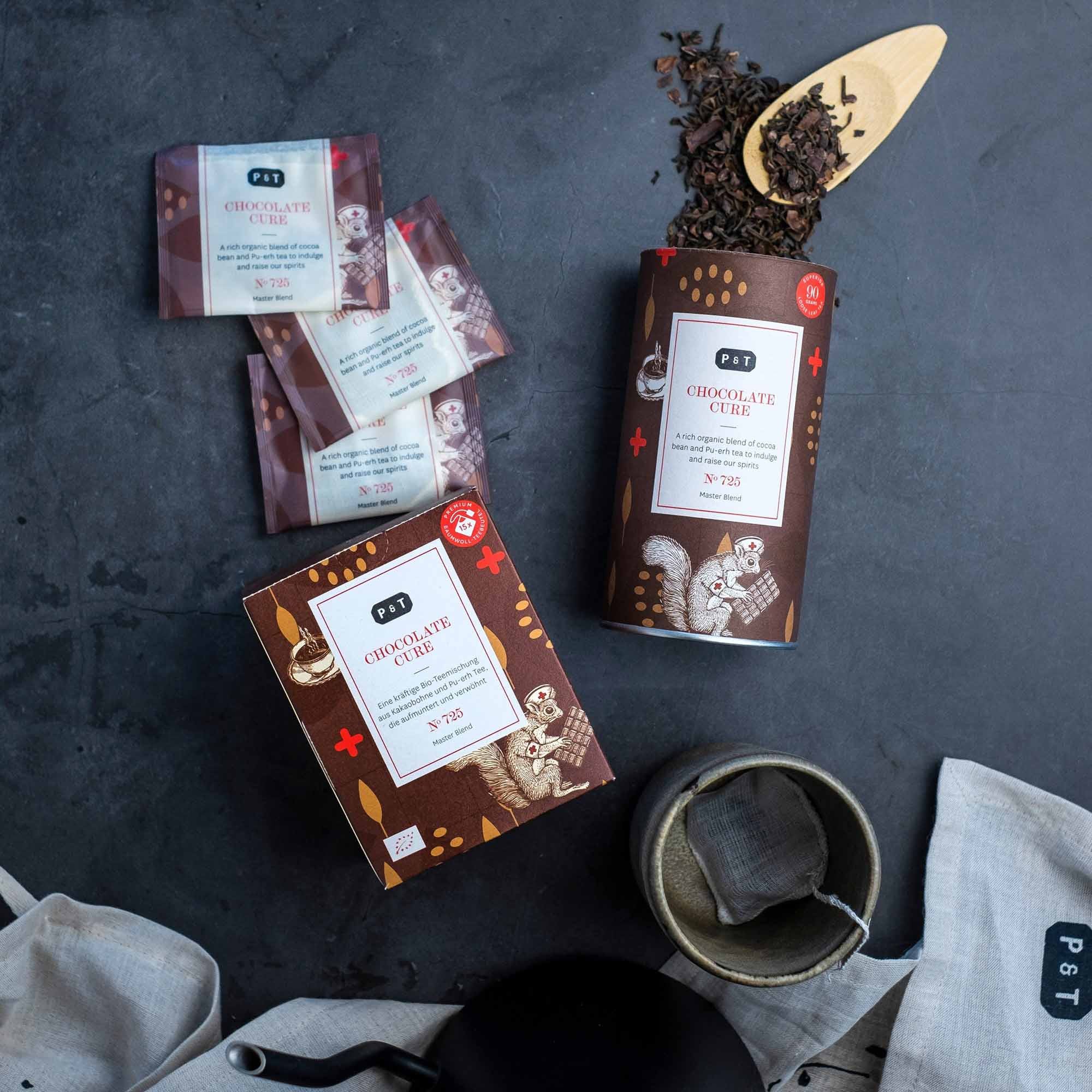 Premium-Bio-Teemischung Chocolate Cure von P & T mit Verpackung, Teebeuteln und Zutaten.
