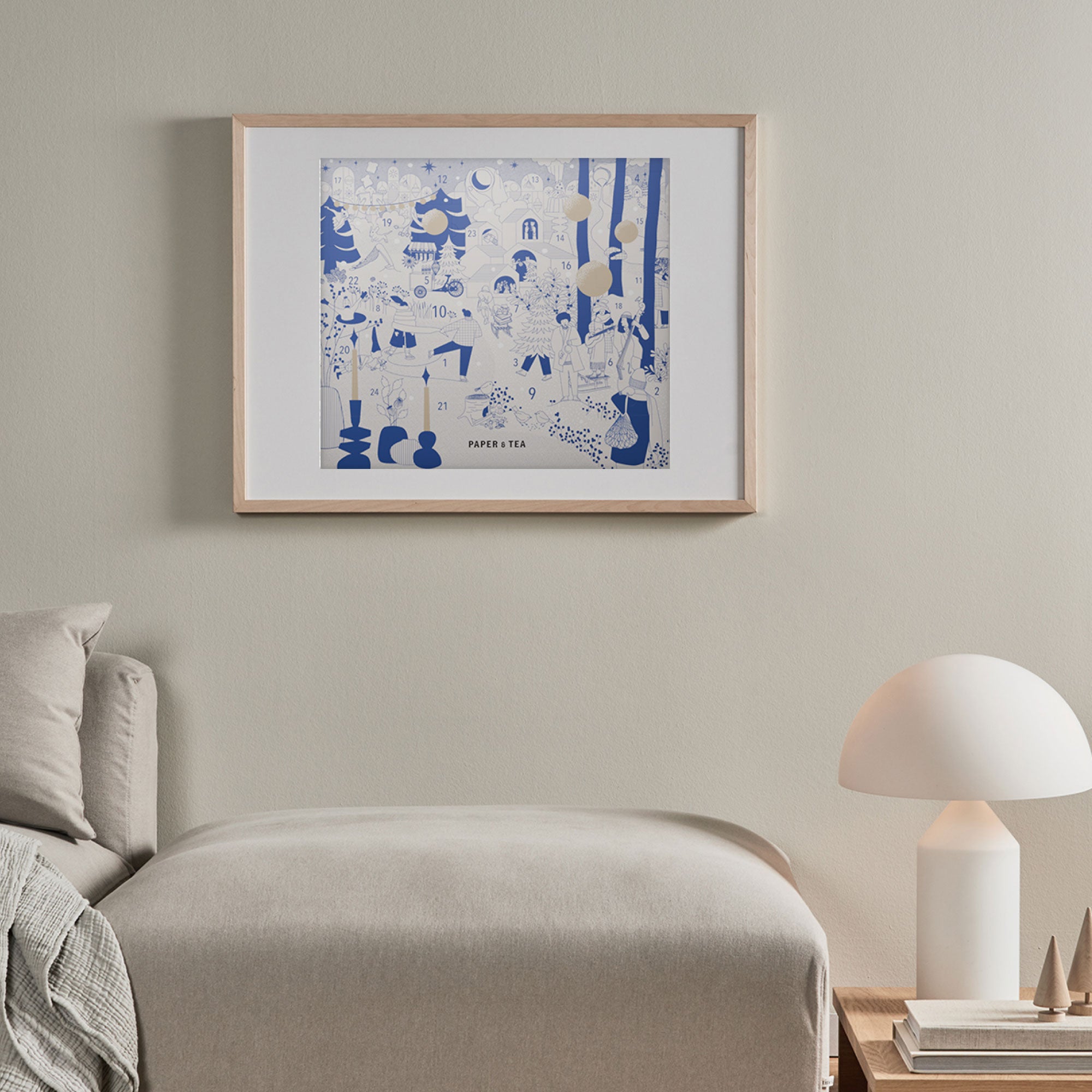 Gemütliche Schlafzimmer-Ecke mit beigem Bett, Holztisch und blau-weißem PAPER & TEA Poster.