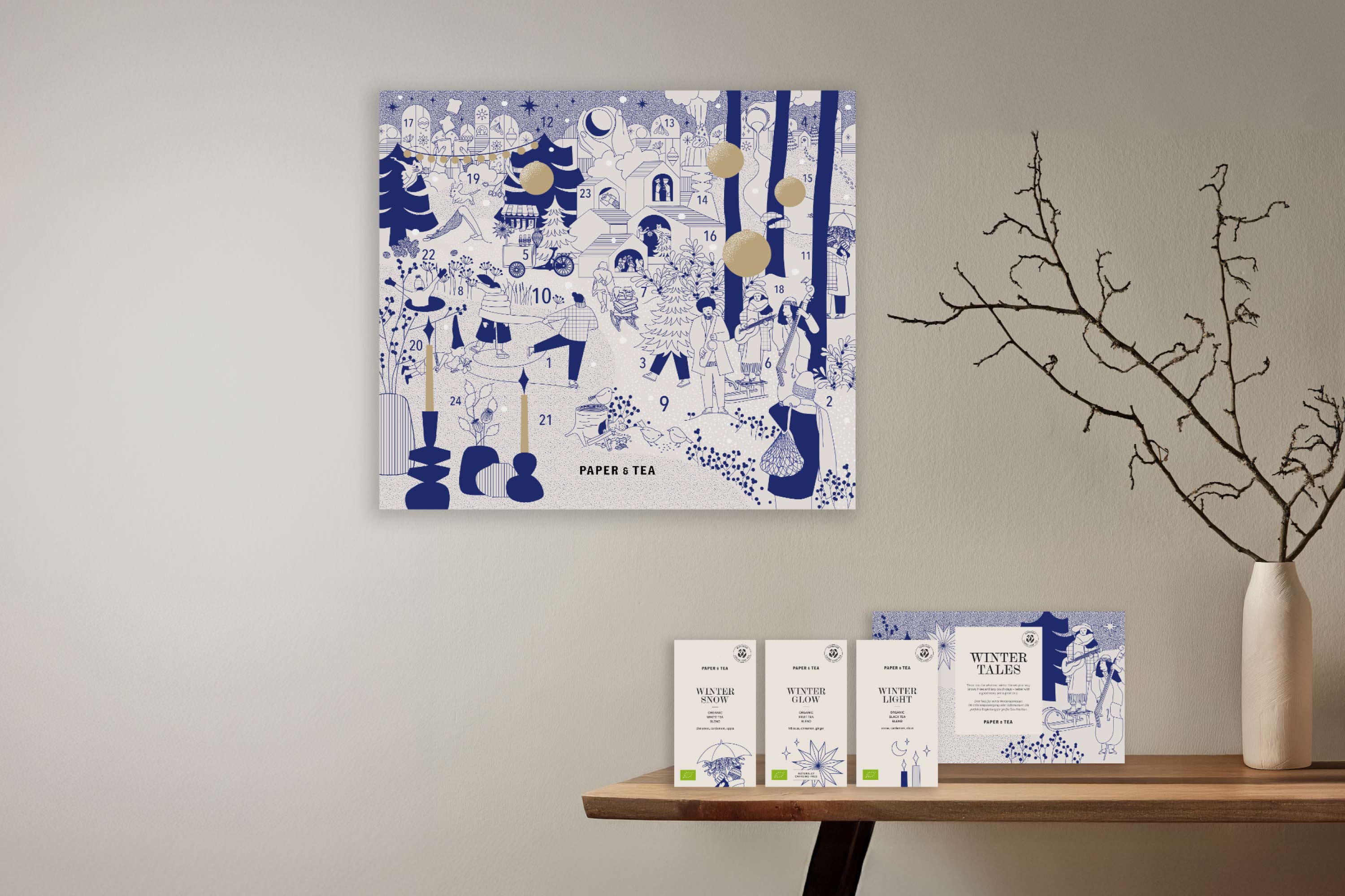 Minimalistischer Adventskalender mit blauen und goldenen Wintermotiven, drei Winter-Teeboxen und einer Karte.